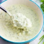 A spoon lifting out healthy tartar sauce from a bowl.