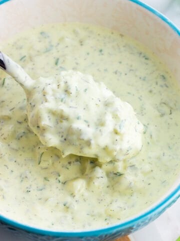 A spoon lifting out healthy tartar sauce from a bowl.