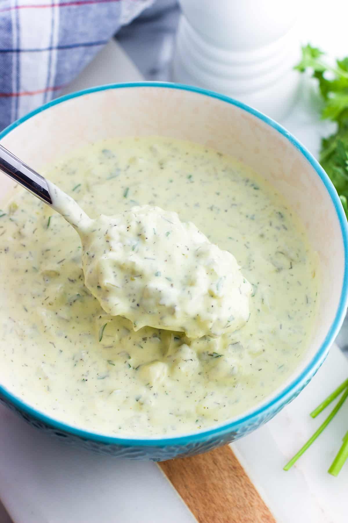 A spoon lifting out healthy tartar sauce from a bowl.