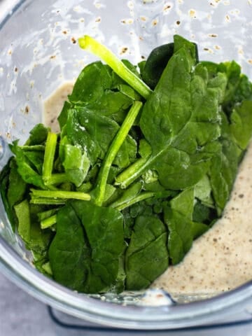 Frozen spinach leaves added to a smoothie in a blender.