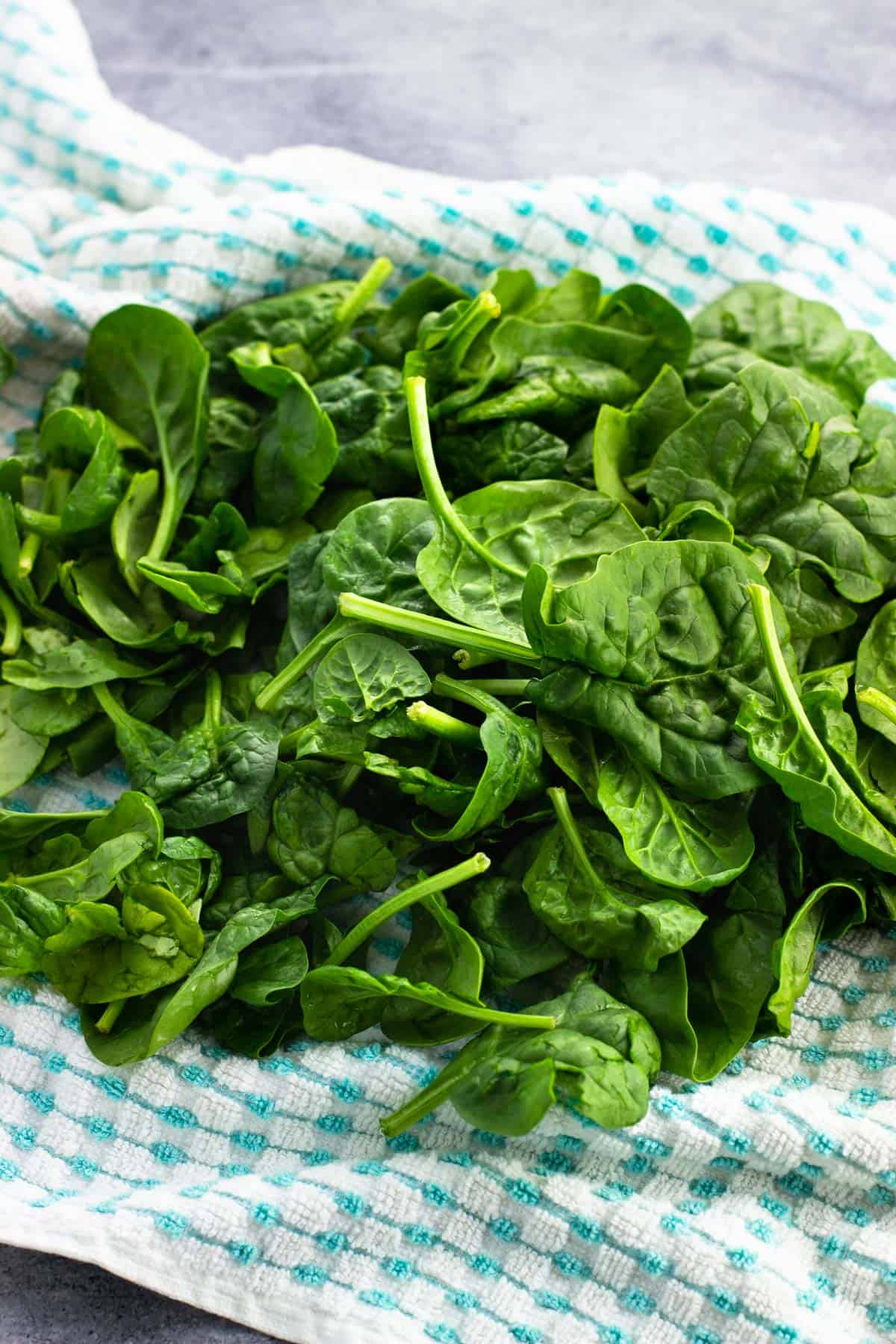 Spinach leaves drying on a kitchen towel.