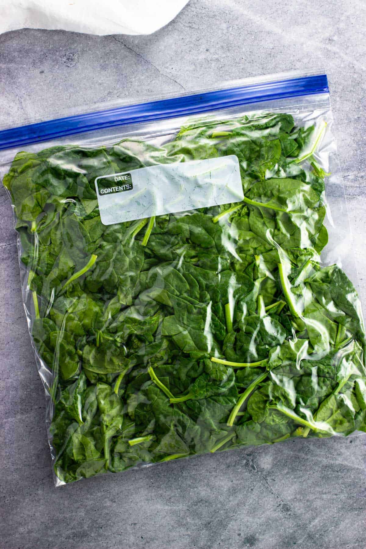 Spinach leaves packed into a gallon plastic bag with the air pressed out.