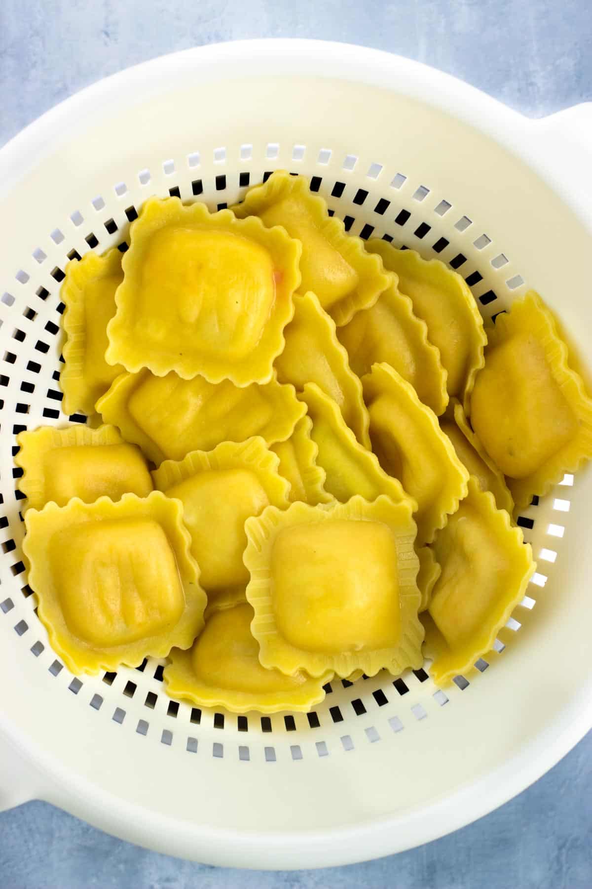 Boiled lobster ravioli in a colander.