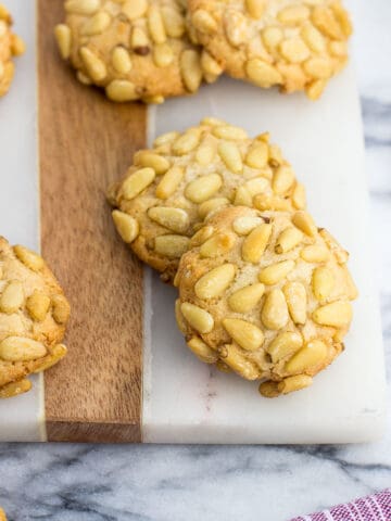 Pignoli cookies on a marble serving board.