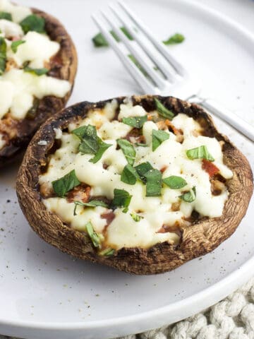 Portobello mushroom pizzas on a plate with a fork.