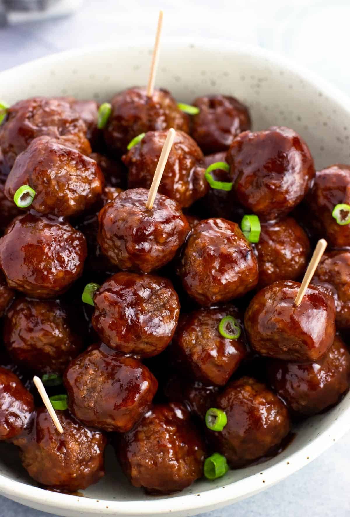 A bowl of cocktail meatballs with toothpicks in them.