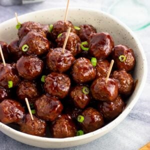 A bowl of cocktail meatballs with toothpicks in them.