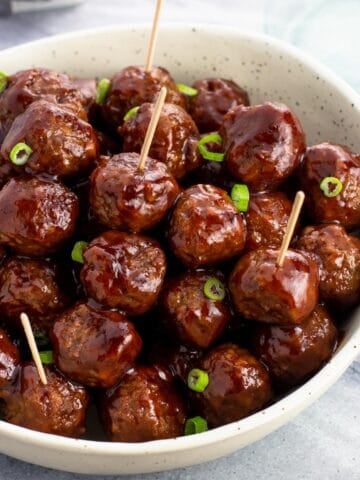 A bowl of cocktail meatballs with toothpicks in them.