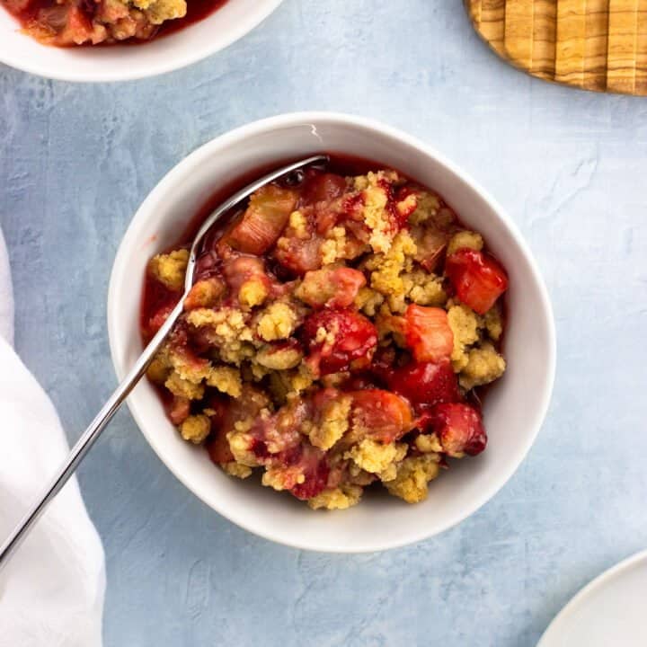 A bowl of strawberry rhubarb crumble with a spoon.