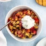 A bowl of strawberry rhubarb crumble topped with ice cream.