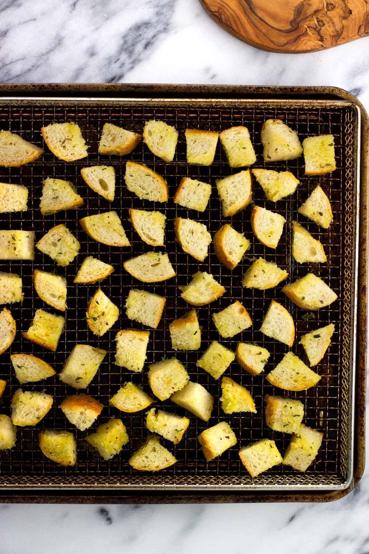 Air fryer croutons on the basket before cooking.