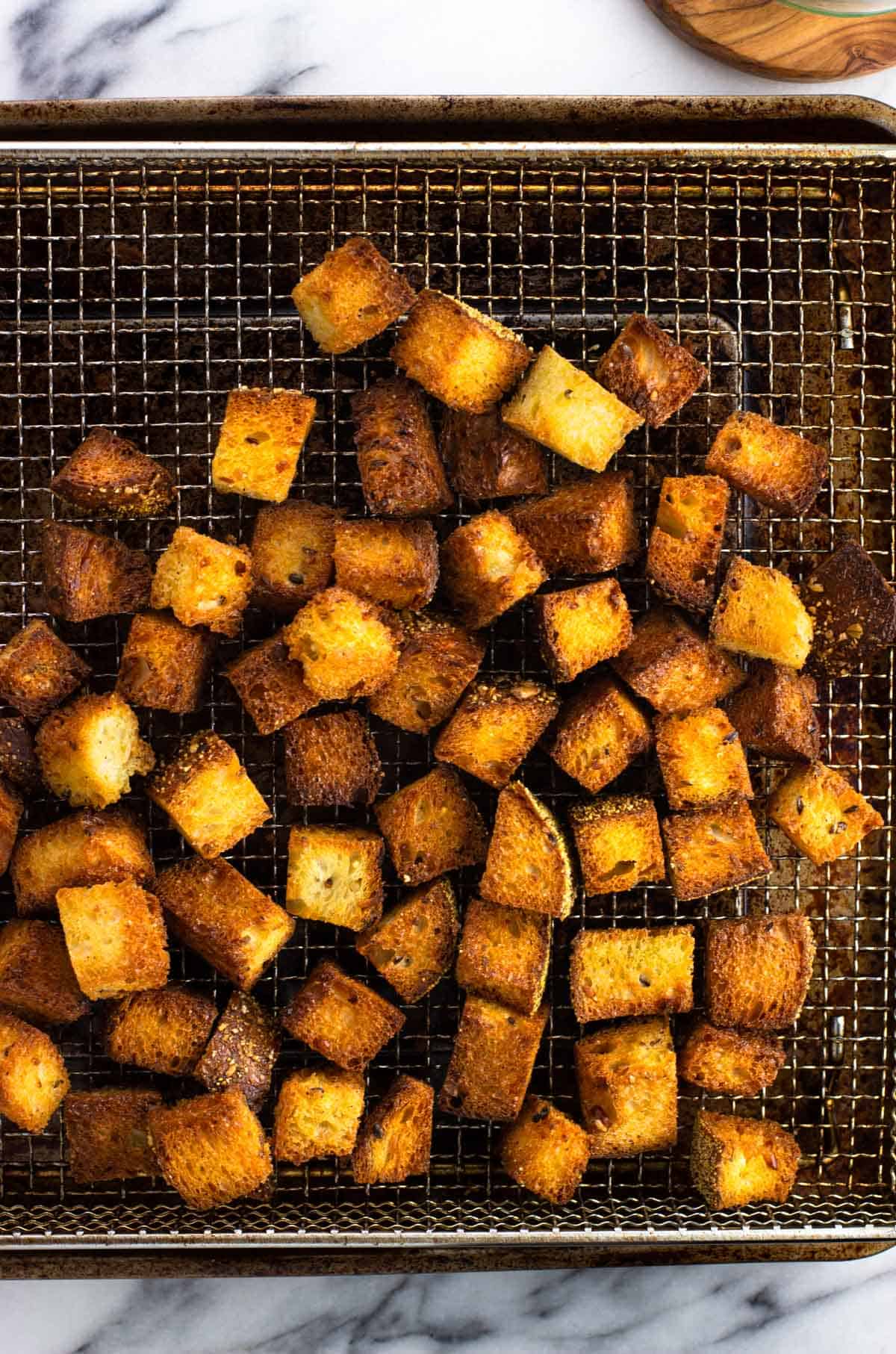 Air fryer croutons on a wire air fryer basket.