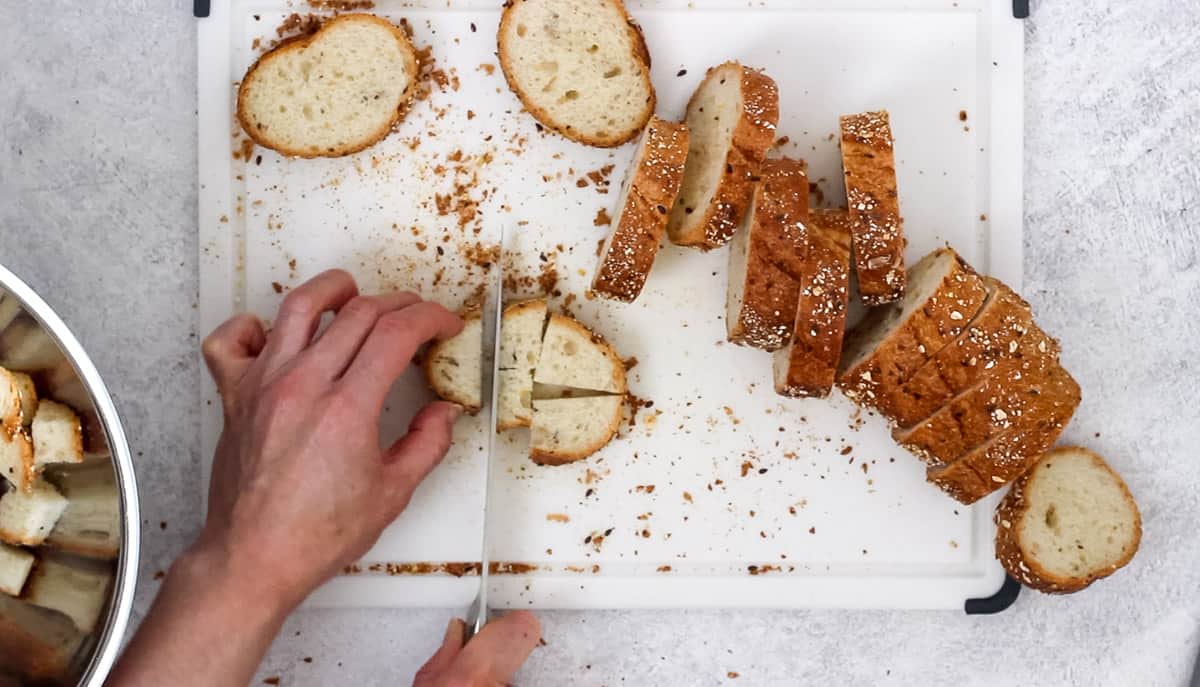 Slicing a baguette into cubes for homemade croutons.