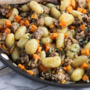 Maple sausage, gnocchi, and sweet potato in a skillet.