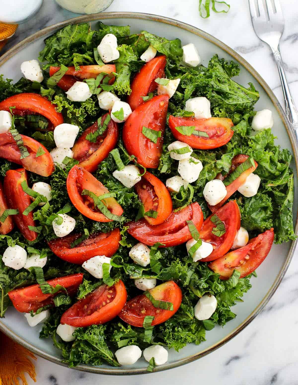 A marinated kale caprese salad on a plate.