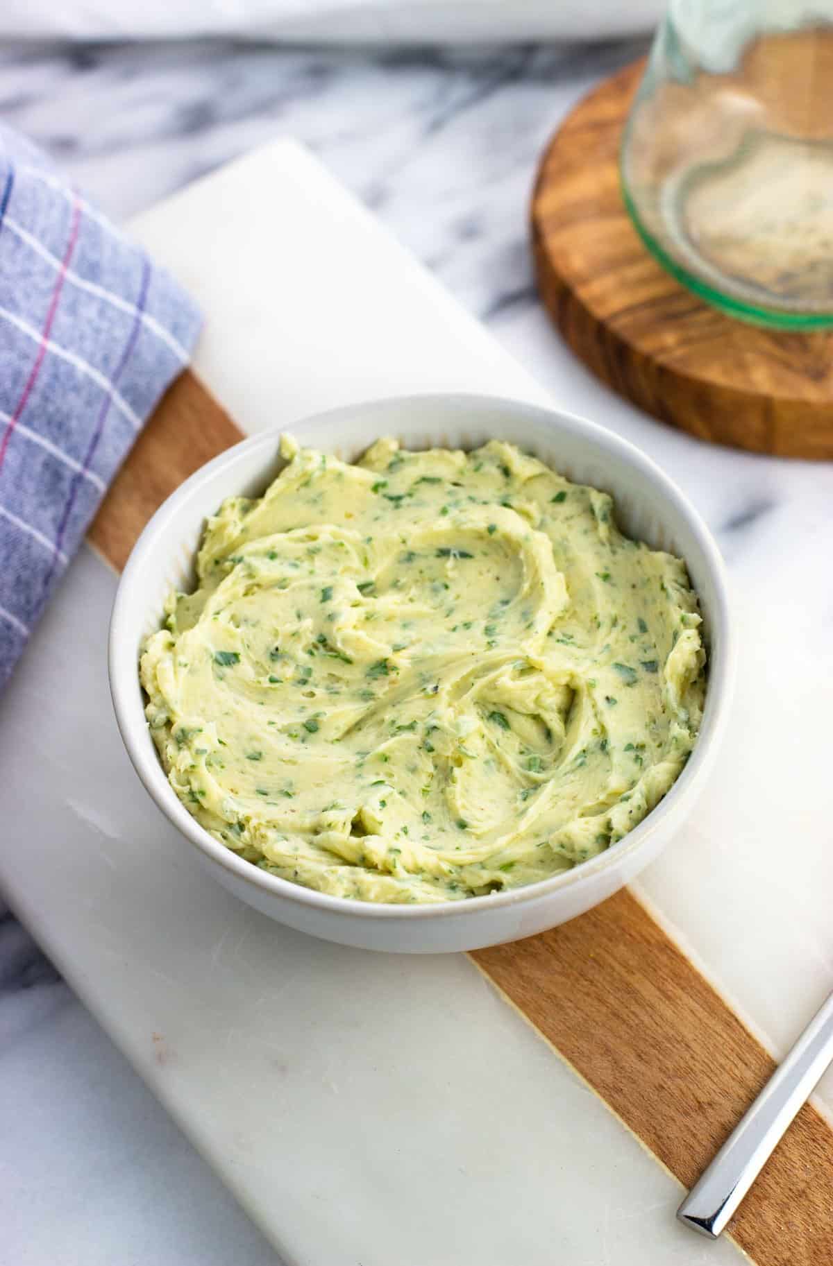 A bowl of roasted garlic butter on a marble board.