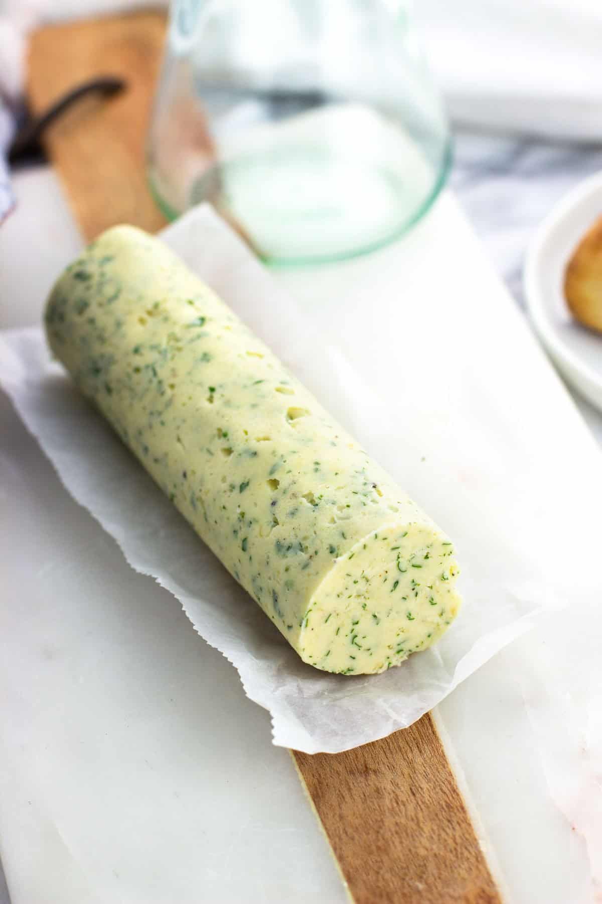 A log of roasted garlic butter on a piece of parchment.