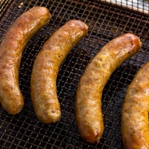 Golden-brown cooked Italian sausages on an air fryer basket.