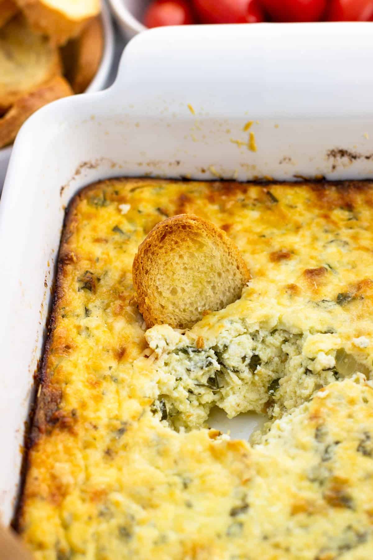 A crostini dipped into the dish of baked ricotta.