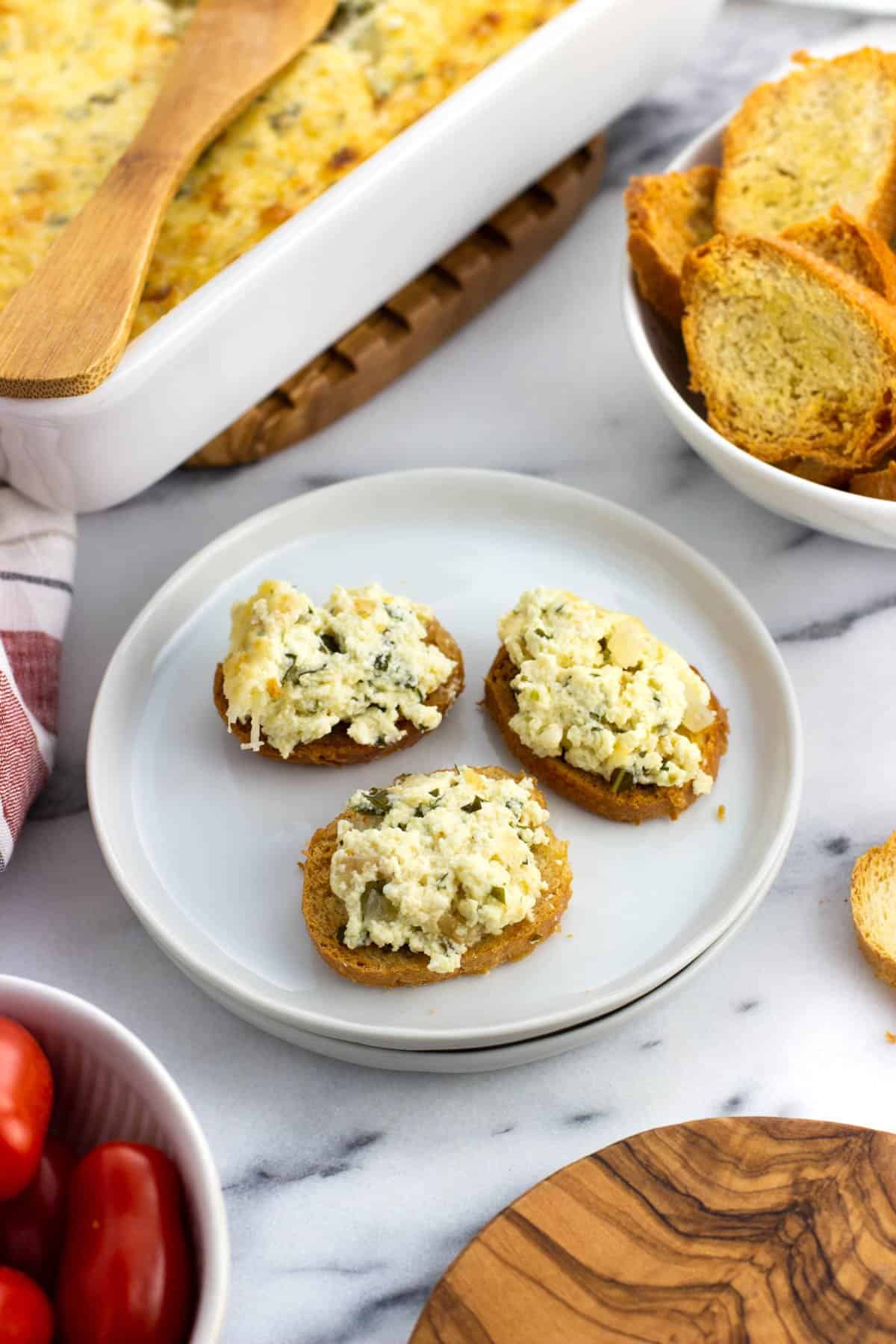 Three crostini topped with baked ricotta on an appetizer plate.