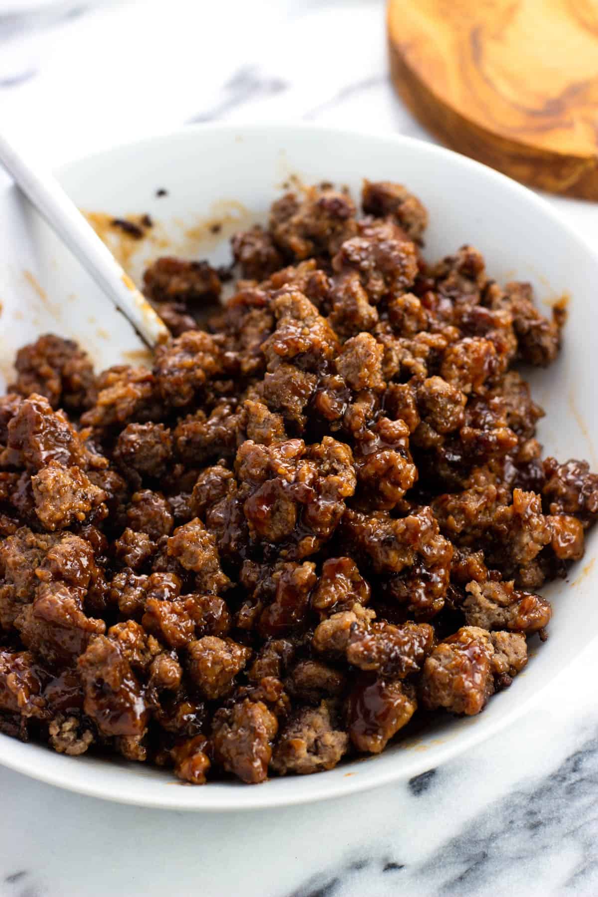 Crumbled ground beef stirred together in a bowl with BBQ sauce.