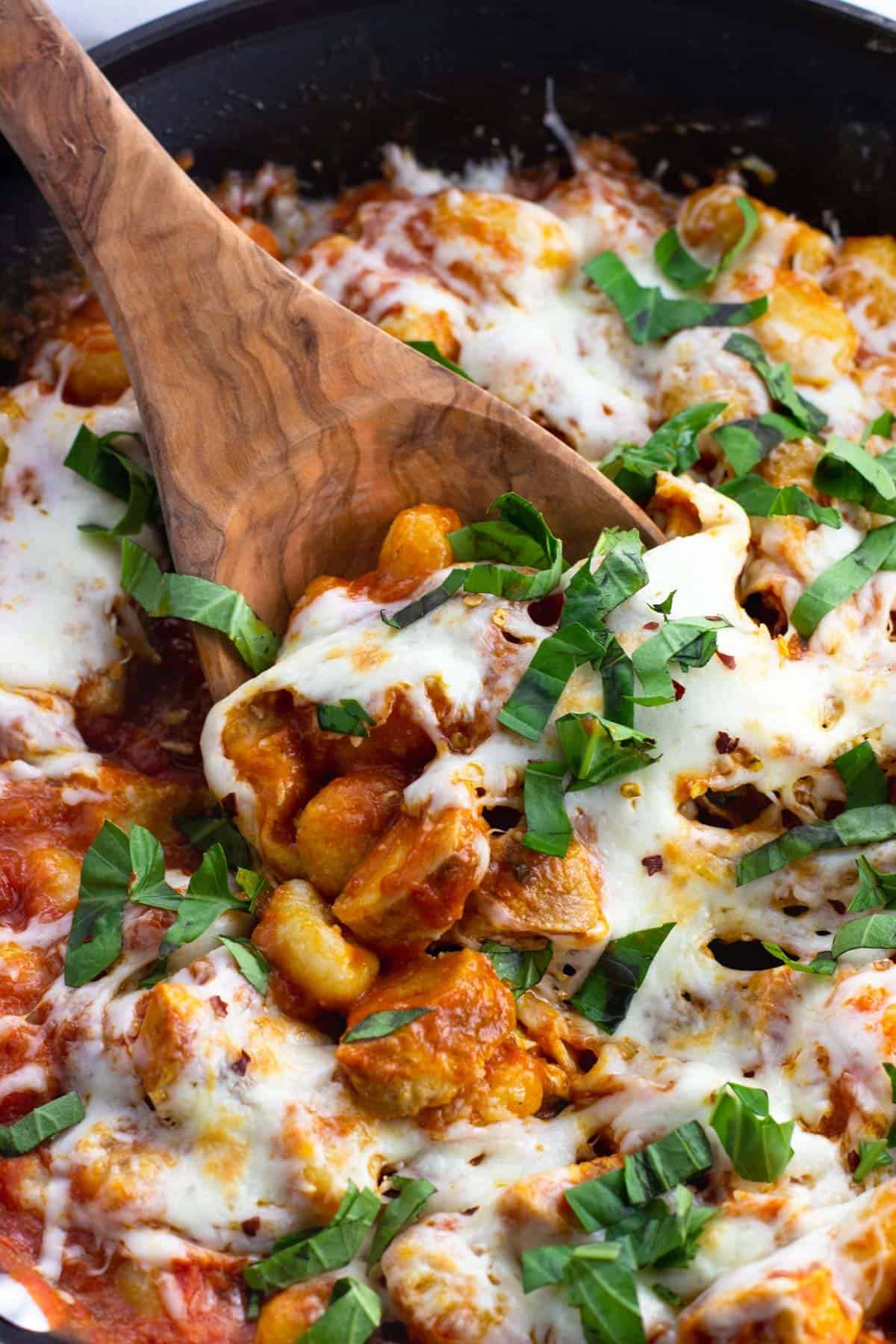 A wooden spoon scooping a serving of the gnocchi.