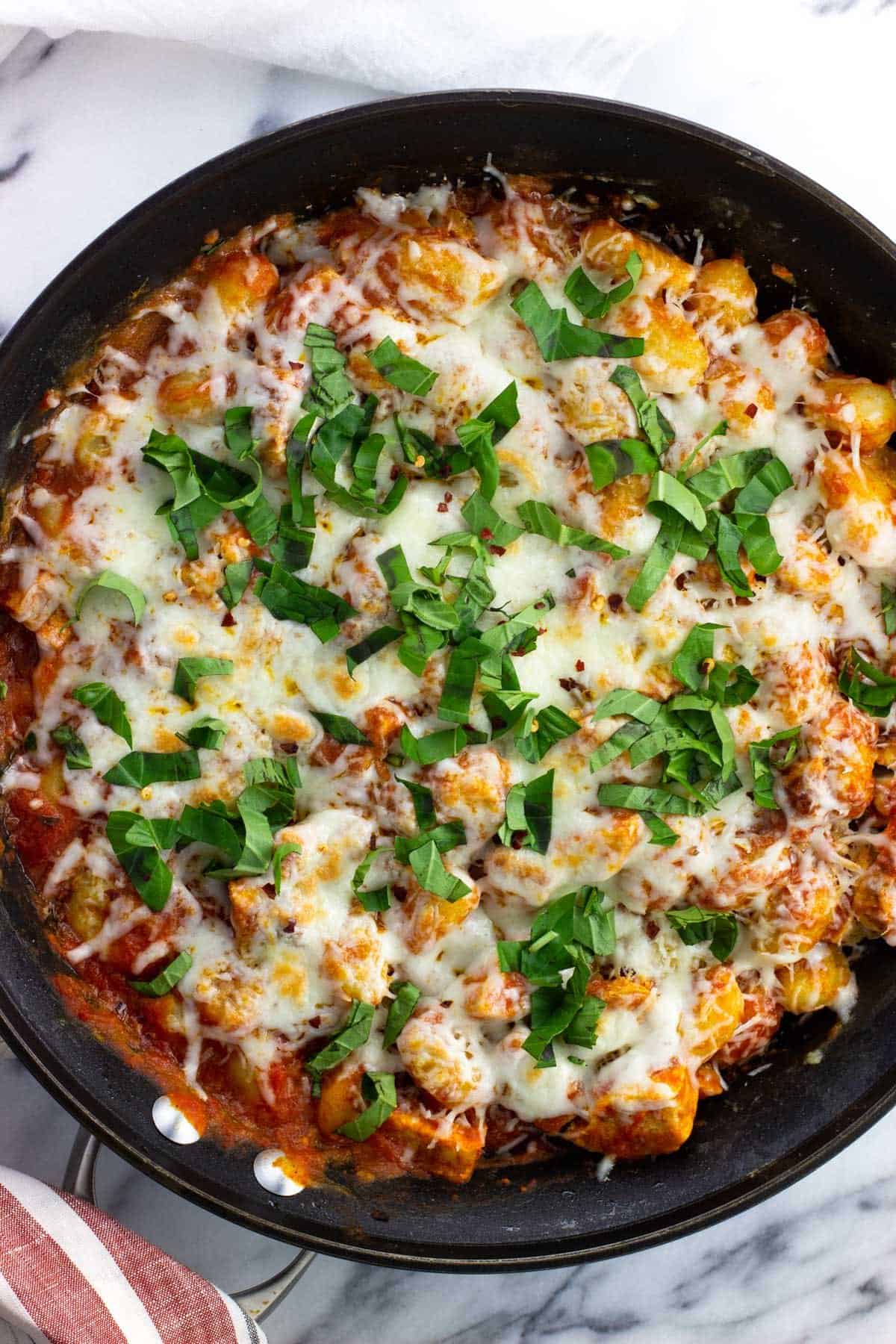 Fresh basil topping the skillet of cooking gnocchi.