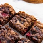 Sliced raspberry brownies on a sheet of parchment.