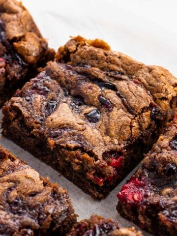 An edge piece of fudgy raspberry brownies on a sheet of parchment.
