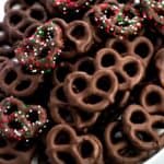 A plate of dark chocolate peppermint pretzels, some covered in holiday red, white, and green sprinkles.