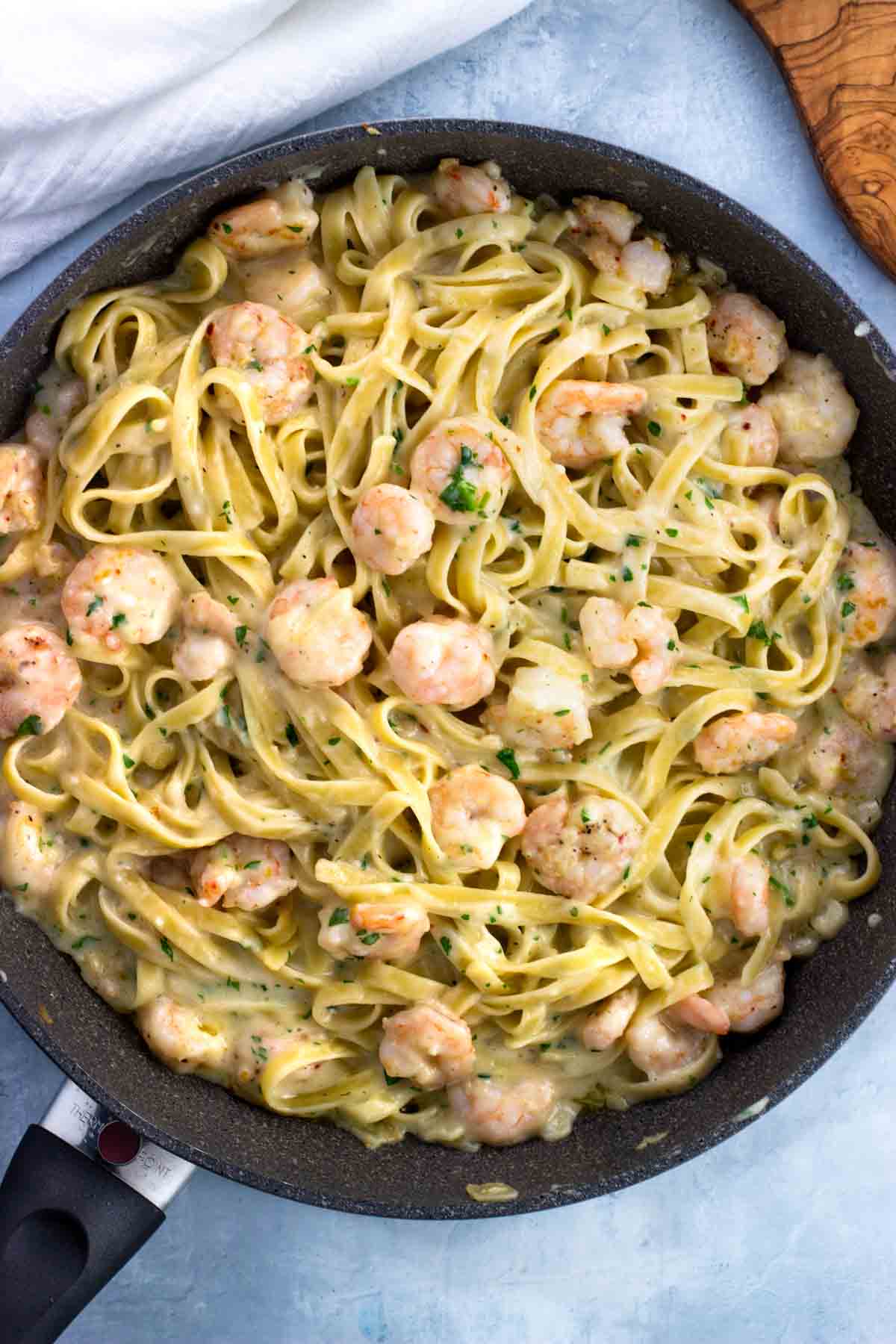 Shrimp alfredo and fettuccine in a skillet.