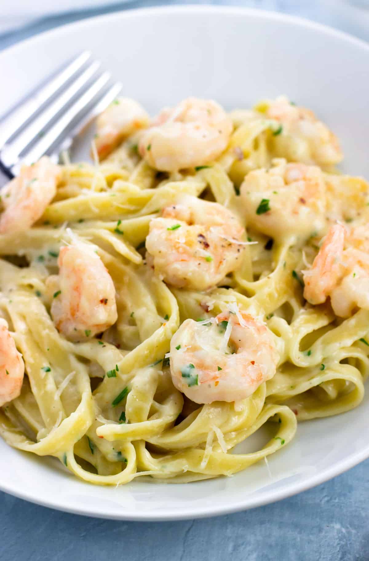 A plate of healthy shrimp alfredo with a fork.