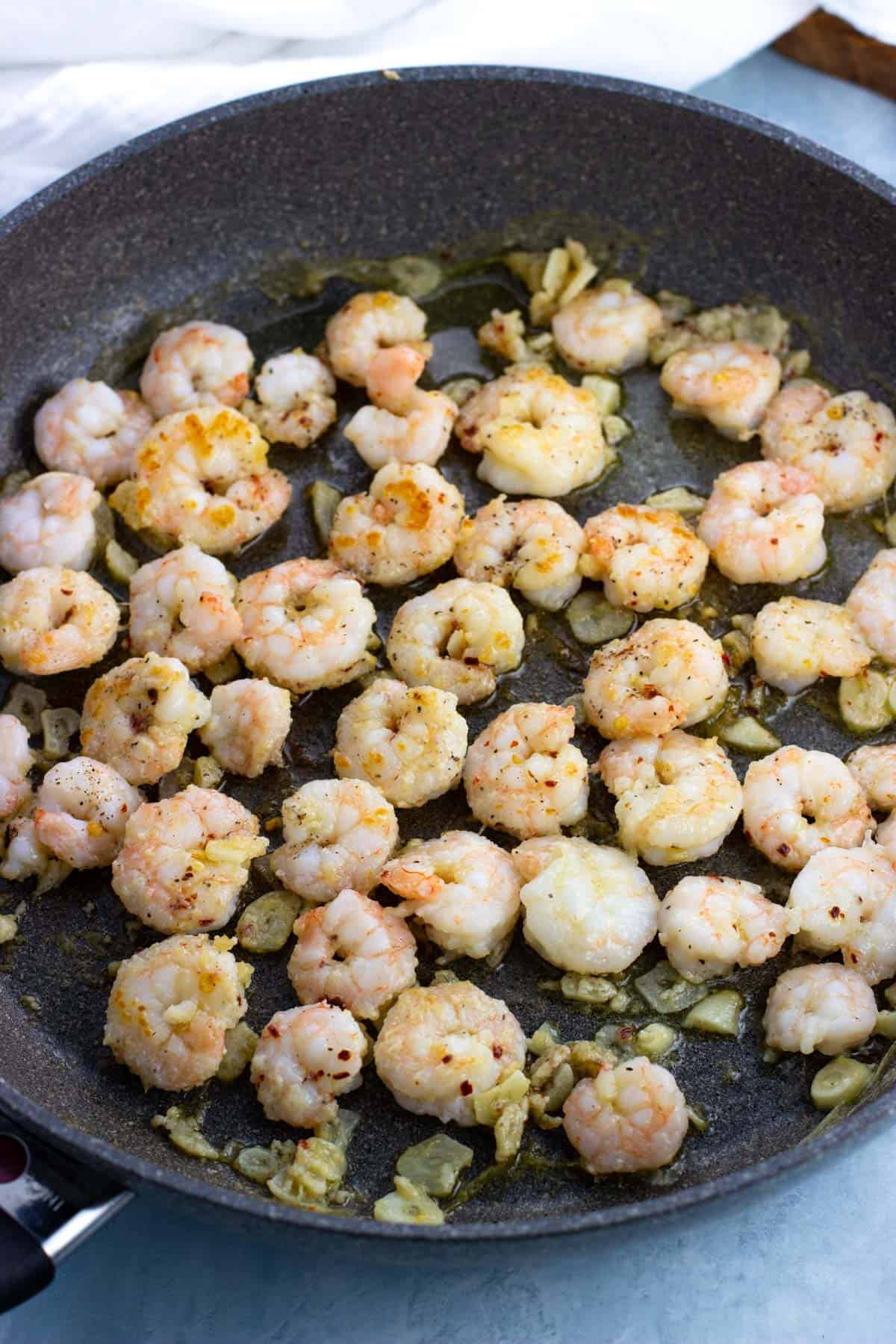 Shrimp and sliced garlic sauteed with olive oil and butter in a pan.