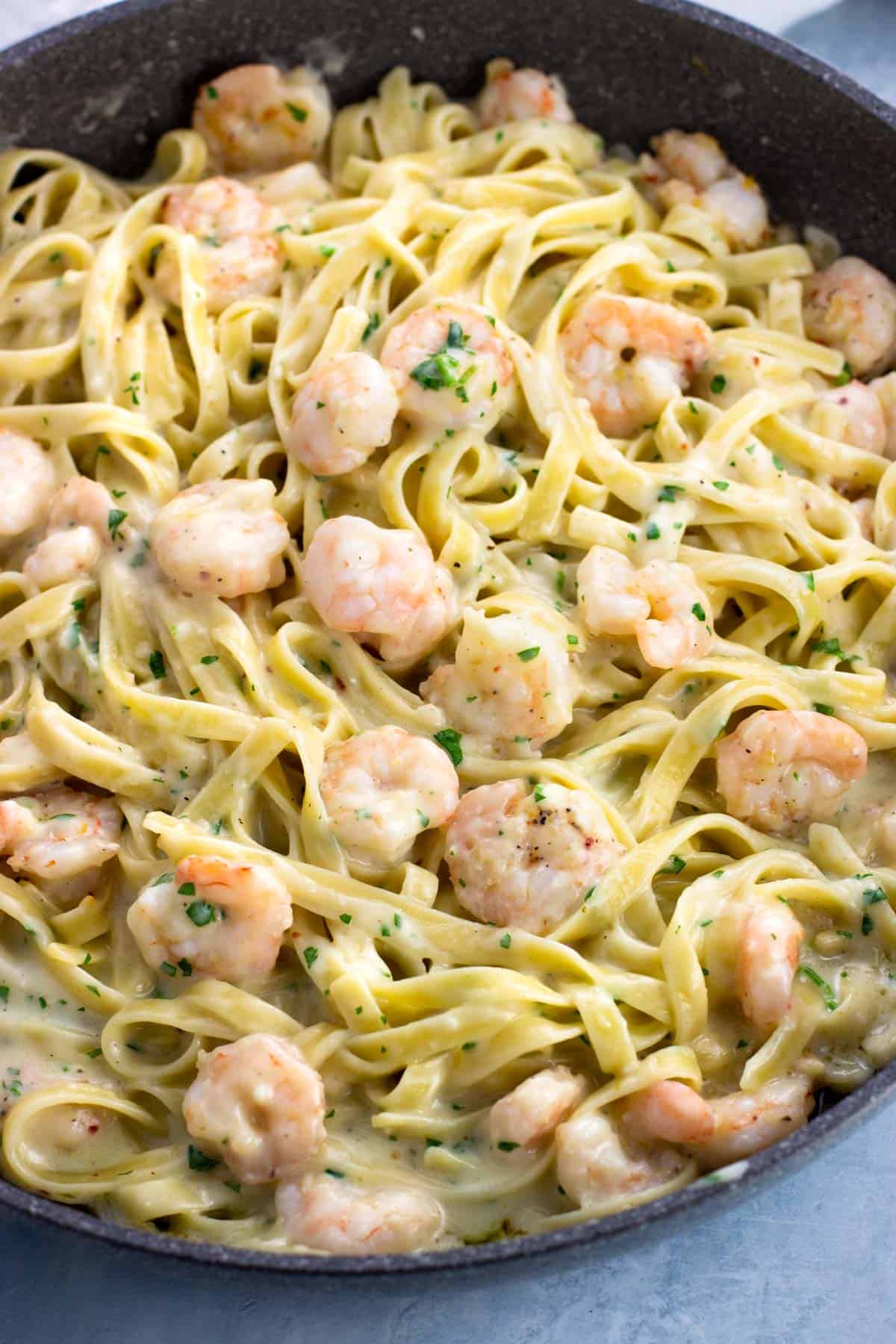 A skillet full of assembled garlic shrimp alfredo.