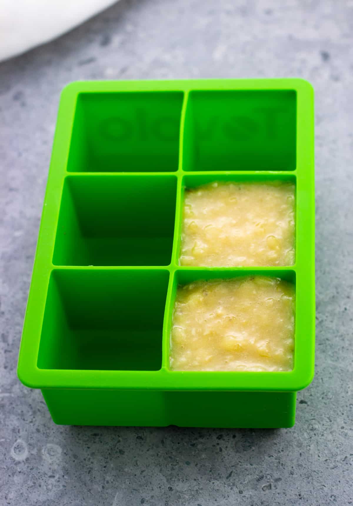 Two wells of a large silicone ice cube tray filled with banana puree.