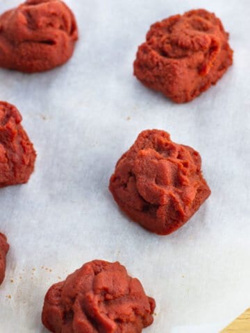 Tablespoon-size blobs of tomato paste on parchment paper.