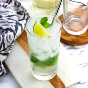 A virgin mojito garnished with lime and mint leaves with a metal straw.