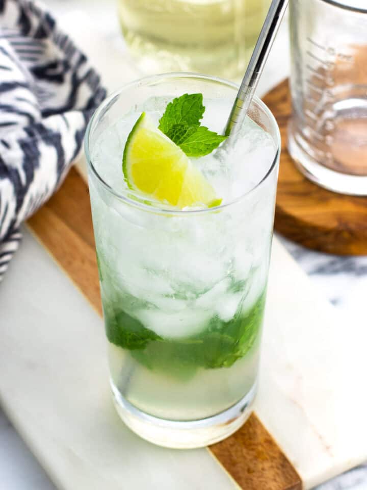 A virgin mojito garnished with lime and mint leaves with a metal straw.