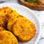 Slices of polenta served on a plate next to pesto and marinara sauce.