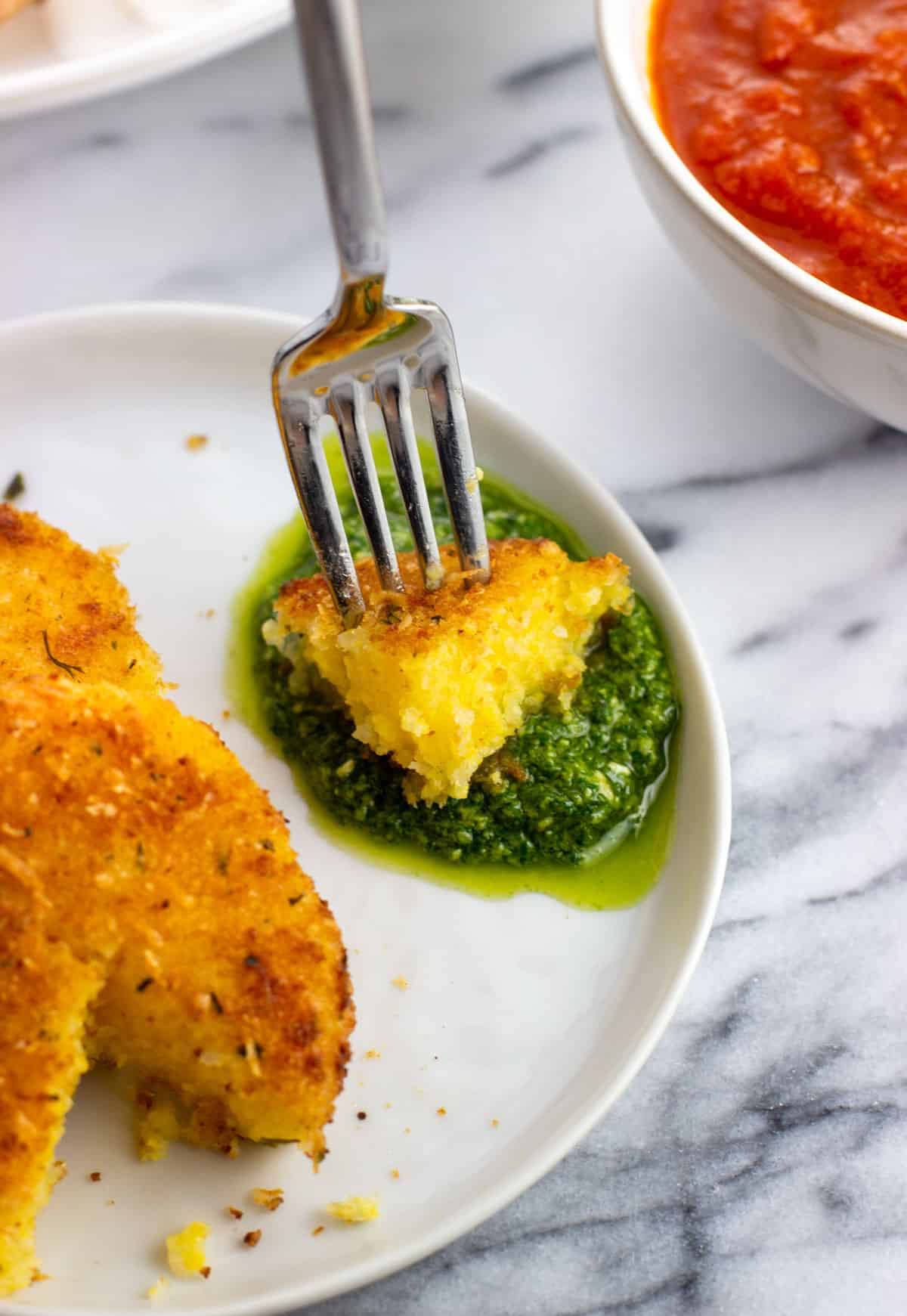 A forkful of polenta being dipped into basil pesto.