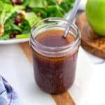 A jar of pomegranate vinaigrette with a spoon in it.