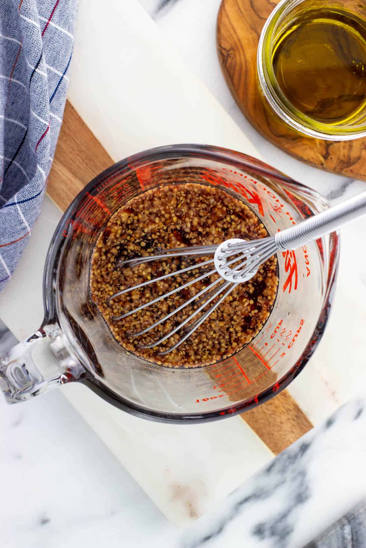 Combined dressing ingredients in a glass measuring cup with a whisk before adding the olive oil.