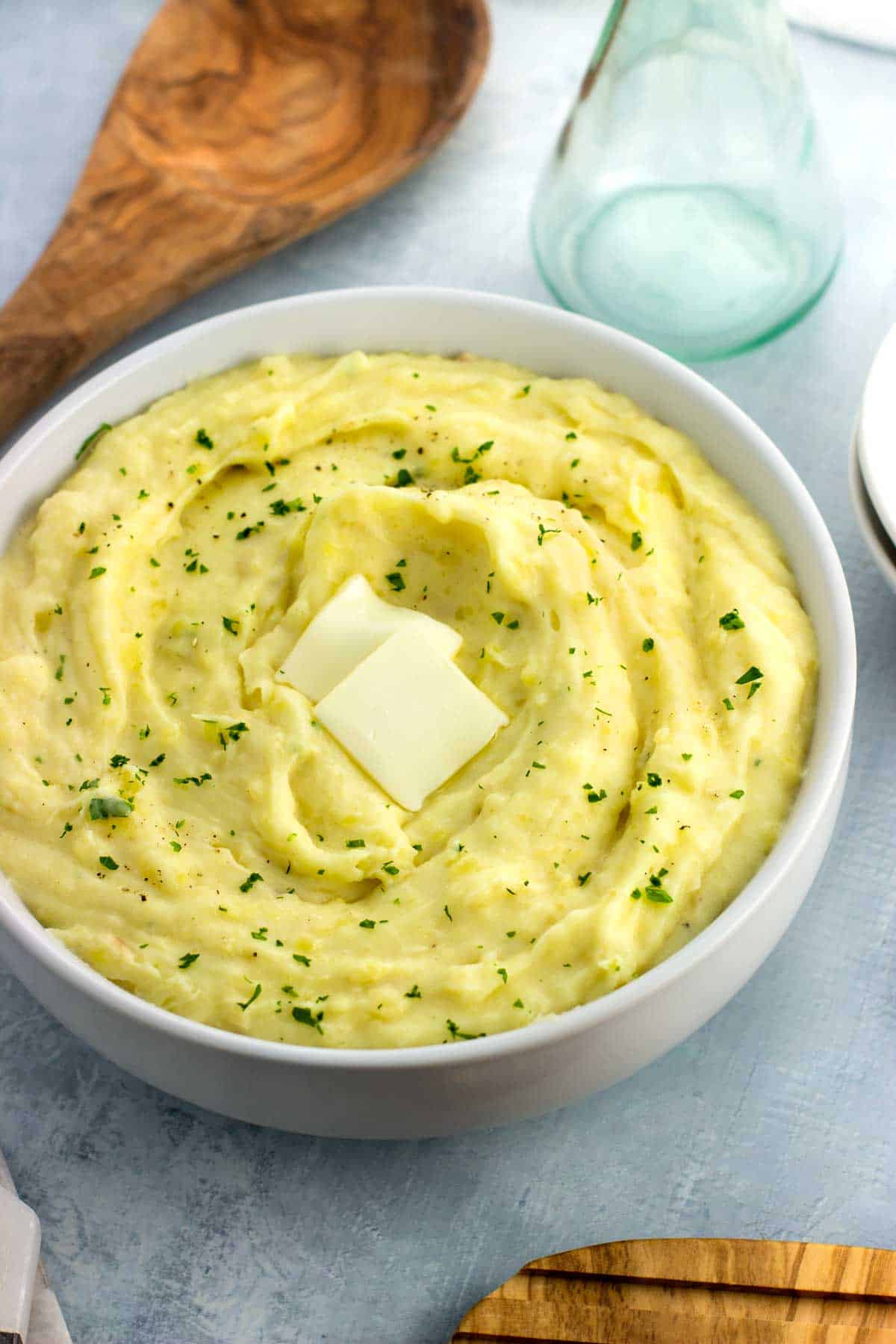 A serving bowl of mashed potatoes topped with a melting pat of butter.