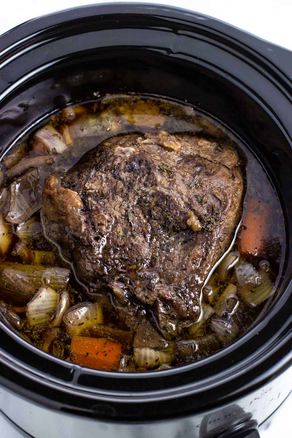 Cooked shoulder roast, vegetables, and gravy in the slow cooker.