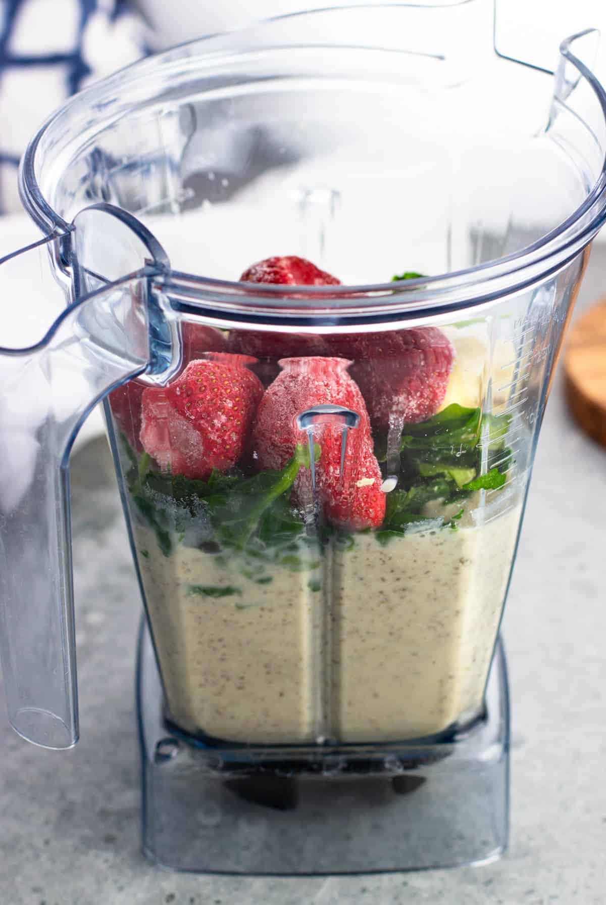 Frozen fruit and spinach added to the blender.