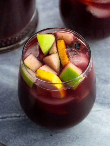 A glass of non-alcoholic sangria filled with fruit.