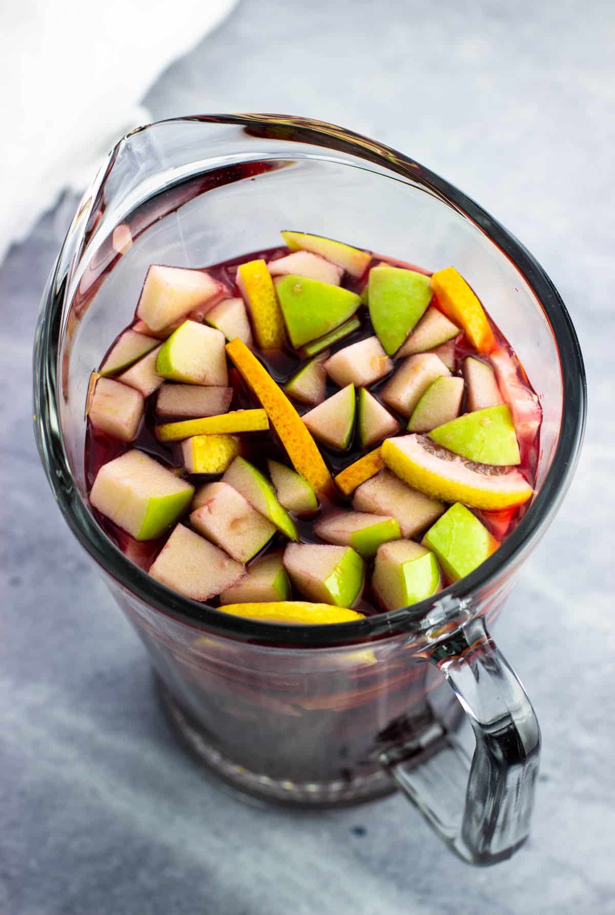 All but the carbonated ingredients added to the pitcher with fruit and cinnamon sticks.