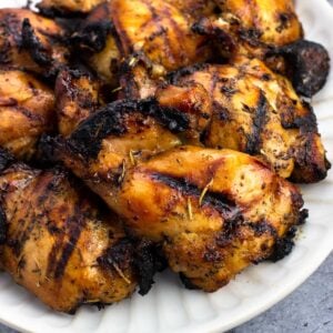 Marinated and grilled boneless skinless chicken thighs on a plate.