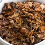 A serving bowl of coffee-rubbed pulled pork drizzled with BBQ sauce.