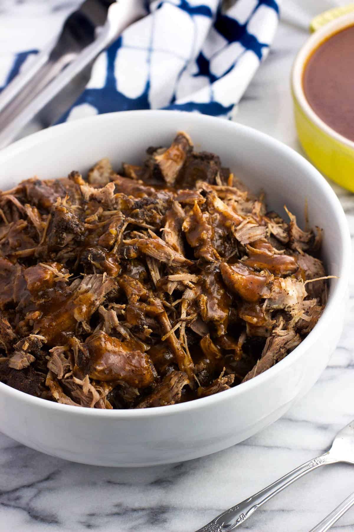 A bowl of Instant Pot pulled pork drizzled with BBQ sauce.
